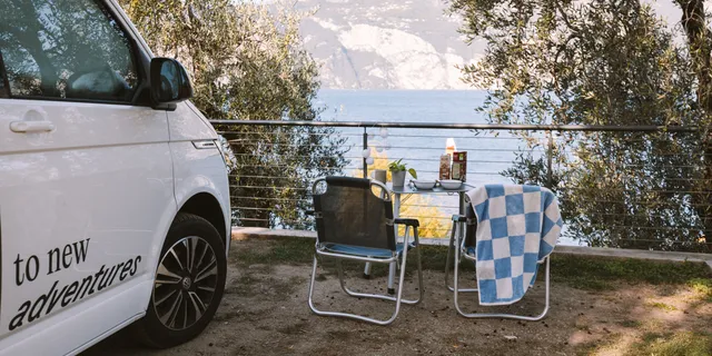 Ein gedeckter Campingtisch vor dem Gardasee in Italien neben einem Off Camper