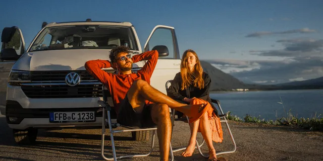 Pärchen sitzt vor Camper in der Dämmerung