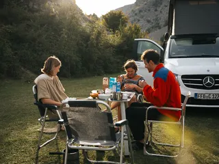 Friends sit on a camping table in the green at the Estonia Camping.